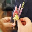 Model Holding Pastel Dried Flower Buttonhole Against Navy Lapel