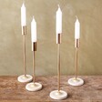 Four Gold Candlestick Holders with Glazed Bases on Wooden Table