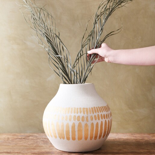 model arranging plants in vase that is sat on table