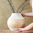 model holding Large Round Hand-Painted Vase in White with greenery inside vase