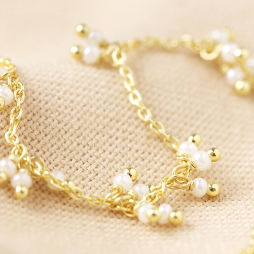 Close Up of Chain and Pearl Cluster Necklace in Gold on Fabric