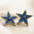 Cobalt Blue Embroidered Star Stud Earrings on Beige Fabric