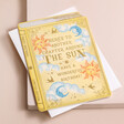 Vintage Novel Around the Sun Birthday Card Laying on White Envelope on Pink Background