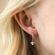 Close Up of Crystal Crescent Moon Huggie Earrings in Gold on Model