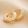 Crystal and Pearl Huggie Hoop Earrings in Gold on Beige Coloured Fabric
