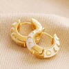 Moon Phase Enamel Huggie Hoop Earrings in Gold on neutral coloured fabric