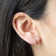 Close Up of Pearl Studded Huggie Hoop Earrings in Gold on Model