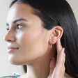 Model Wearing Stone and Pearl Drop Huggie Hoop Earrings in Gold with Hand Behind Ear