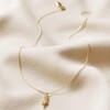 Feminine Figure Pendant Necklace in Gold Full Length on Beige Material