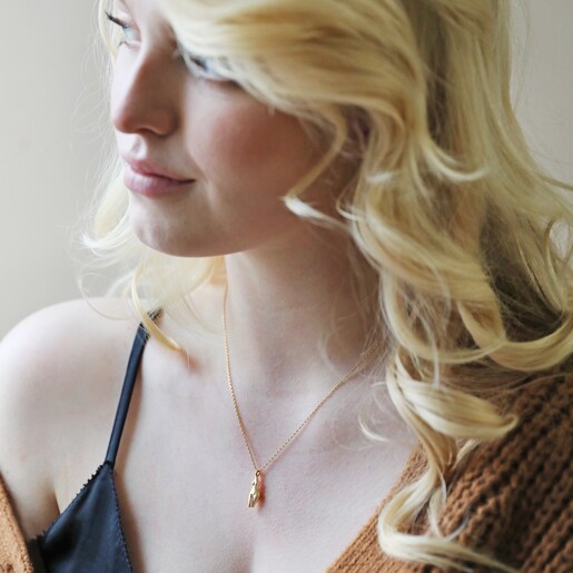 Model Looking to Side Wearing Feminine Figure Pendant Necklace in Gold