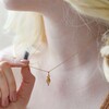 Model Wearing Feminine Figure Pendant Necklace in Gold Holding Between Fingers