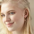Model Smiling Wearing Hanging Sloth Huggie Hoop Earrings in Rose Gold