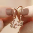 Model Holding Hanging Sloth Huggie Hoop Earrings in Rose Gold