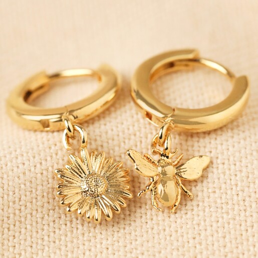 Mismatched Daisy and Bee Huggie Hoop Earrings in Gold on Beige Fabric