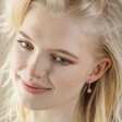Model Smiling Wearing Mismatched Daisy and Bee Huggie Hoop Earrings in Gold