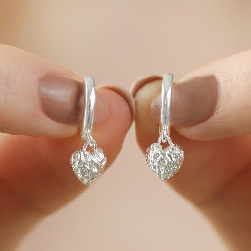 Model Holding Molten Heart Huggie Hoop Earrings in Silver