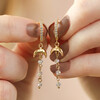 Model Holding Moon and Crystal Drop Chain Huggie Hoop Earrings in Gold