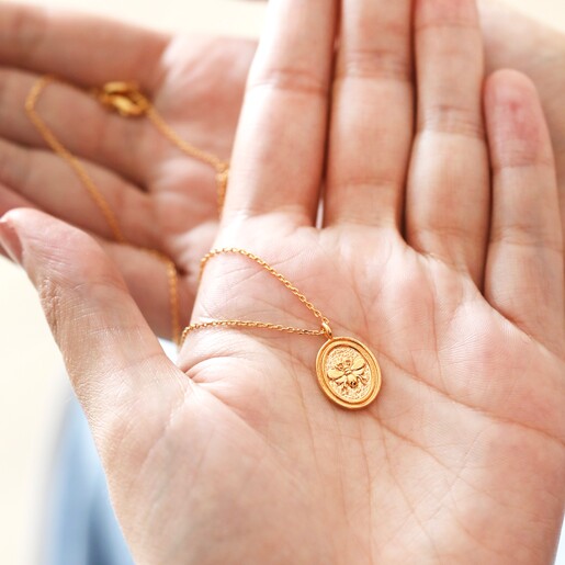 Necklace holding Bee Oval Disc Pendant Necklace in Gold in palm of hand