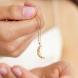 Model holding Colourful Crystal Crescent Moon Hammered Pendant Necklace in Gold dangling on hand