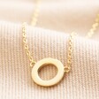 Close up of Eternity Ring Pendant Necklace in Gold on beige coloured fabric