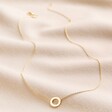 Eternity Ring Pendant Necklace in Gold full length on neutral coloured material