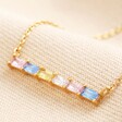 Close up of pendant on Pastel Baguette Crystal Bar Pendant Necklace in Gold on neutral material