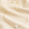 Pearl Heart Charm Necklace in Gold Full Length on Beige Coloured Material