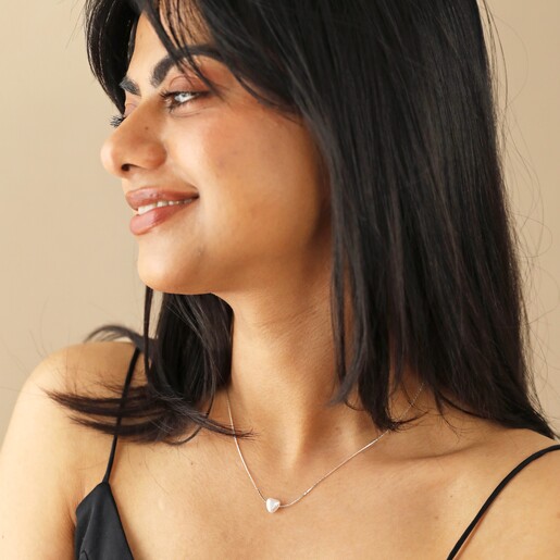 Model Smiling Looking to Side Wearing Pearl Heart Charm Necklace in Silver