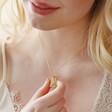 Close up of Personalised Wildflower Envelope Locket Pendant Necklace in Gold on model holding locket between fingers