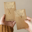 Model Holding Set of 2 Friendship Heart Pendant Necklaces in Gold in Packaging