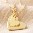 Set of 2 Friendship Heart Pendant Necklaces in Gold Overlapped on Neutral Fabric