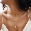 Close Up of Model Wearing Stamped Star Pendant Necklace in Gold with Other Necklaces