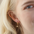 Close Up of Opal Sun Huggie Hoop Earrings in Gold on Model