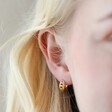 Close Up of Model Wearing Tiny Woven Huggie Hoop Earrings in Gold