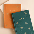 Personalised Initials Bee Fabric Notebooks in orange and teal on plain surface