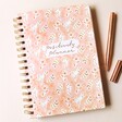 Front Cover of Pink Floral Positivity Planner with Pens on Beige Coloured Background