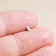 Model Holding Tish Lyon Solid White Gold Crescent Moon Helix Earring Between Fingertips