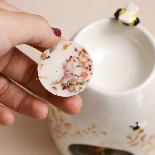Model holding The Candle Brand Peony and Rose Wax Melts above wax burner
