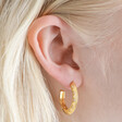 Close Up of Estella Bartlett Geometric Crystal Hoop Earrings in Gold on Model 