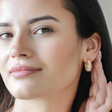Model Wearing Estella Bartlett Chunky Flower Dome Hoops in Gold with Hand Behind Ear