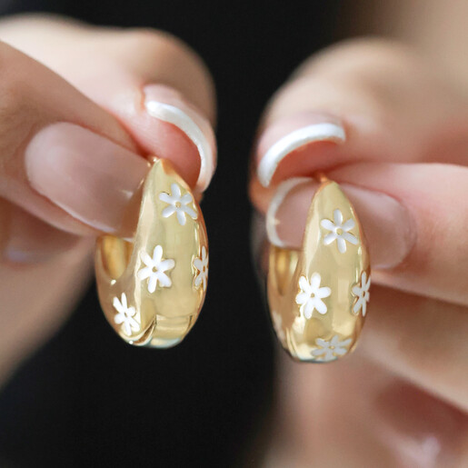 Model Holding Estella Bartlett Chunky Flower Dome Hoops in Gold in Front