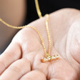 Model Holding Estella Bartlett Flower T-Bar Necklace in Gold in Palm