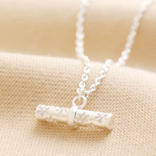Close Up of Estella Bartlett Flower T-Bar Necklace in Silver on Neutral Coloured Fabric
