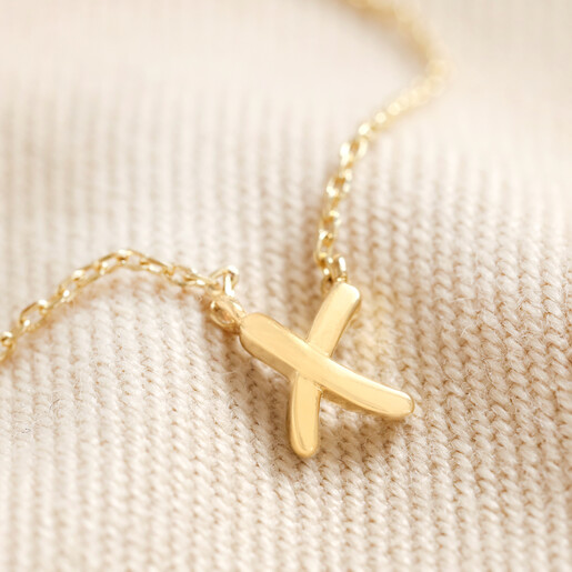 Estella Bartlett Kiss Necklace In Gold Close Up on Beige Fabric