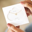 Model holding Estella Bartlett Kiss Necklace In Gold in packaging 