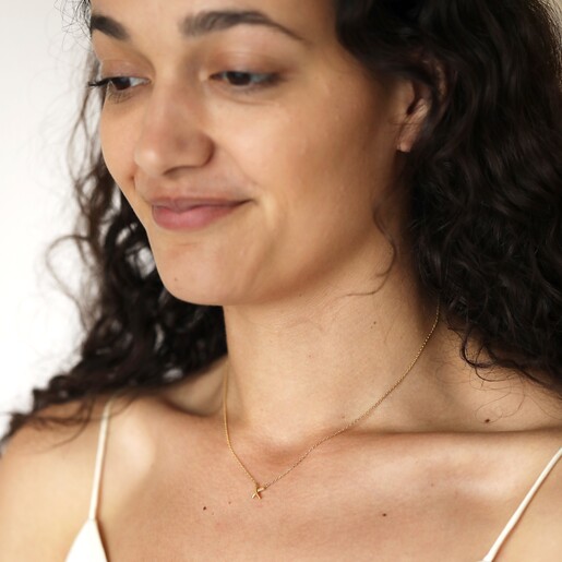 Model smiling wearing Estella Bartlett Kiss Pendant Necklace In Gold