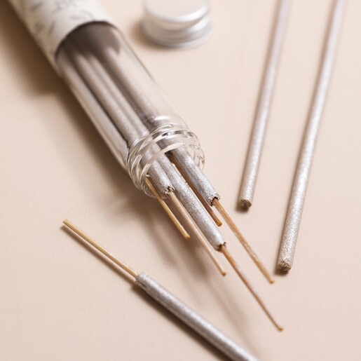 East of India Geranium Incense Sticks Pulled Out of Glass Jar on Beige Background