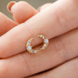 Model Holding Crystal and Opal Crescent Moon Stud Earrings in Gold