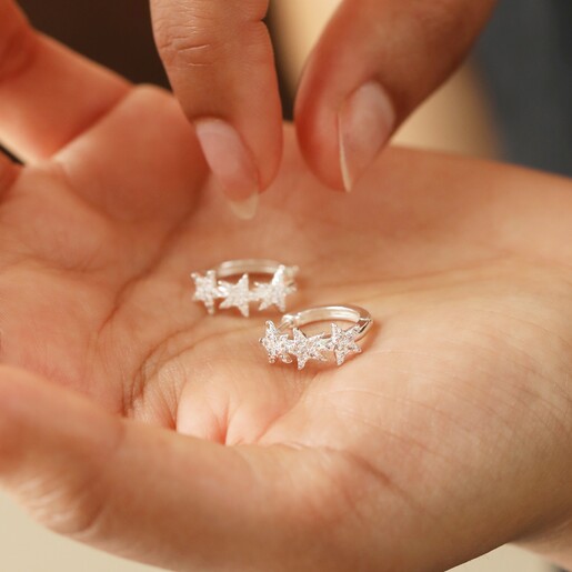 Model Holding Crystal Triple Star Huggie Hoop Earrings in Silver
