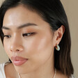Model Looking to Side Wearing Mint Green Organic Resin Hoop Earrings in Gold with Beige Background